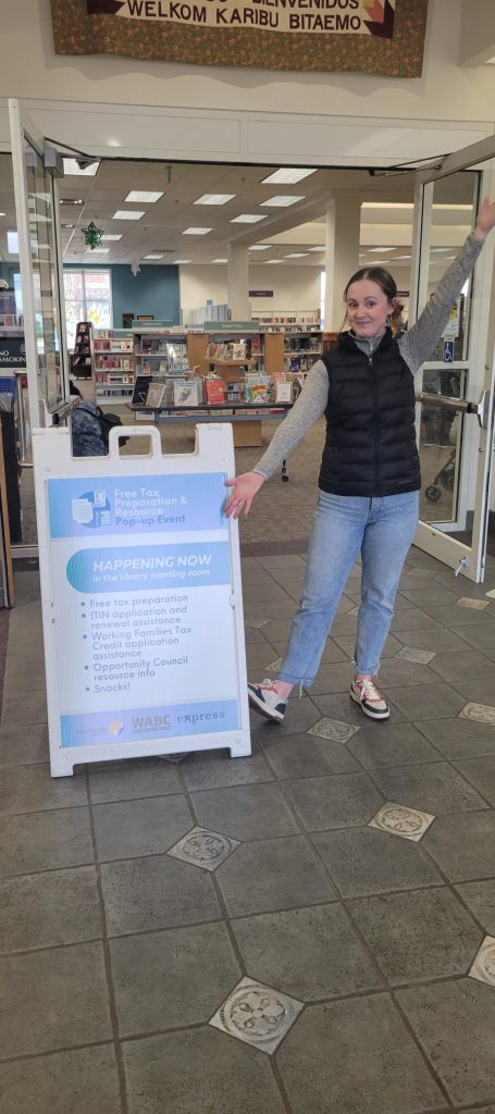 a woman standing next to a sign in a library