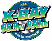 Logo in bold text in a blue-to-yellow gradient saying "K-Bay: 98.9 FM, 930 AM" over a black-and-white pinstriped circle with green and blue borders. The subheading reads "Re-Live Your Favorites Every Day!"