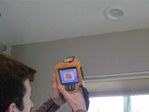 admin_blog_CECInfraredCamera_2023-05 A staff member looks at an infrared camera pointed at a can light on the ceiling of a home.