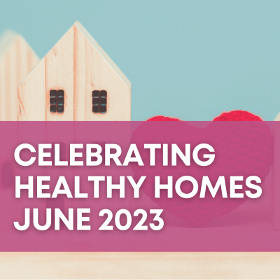 A picture of a wooden model of a home with a crochet heart next to it and a magenta banner with white text saying "Celebrating healthy homes: June 2023"