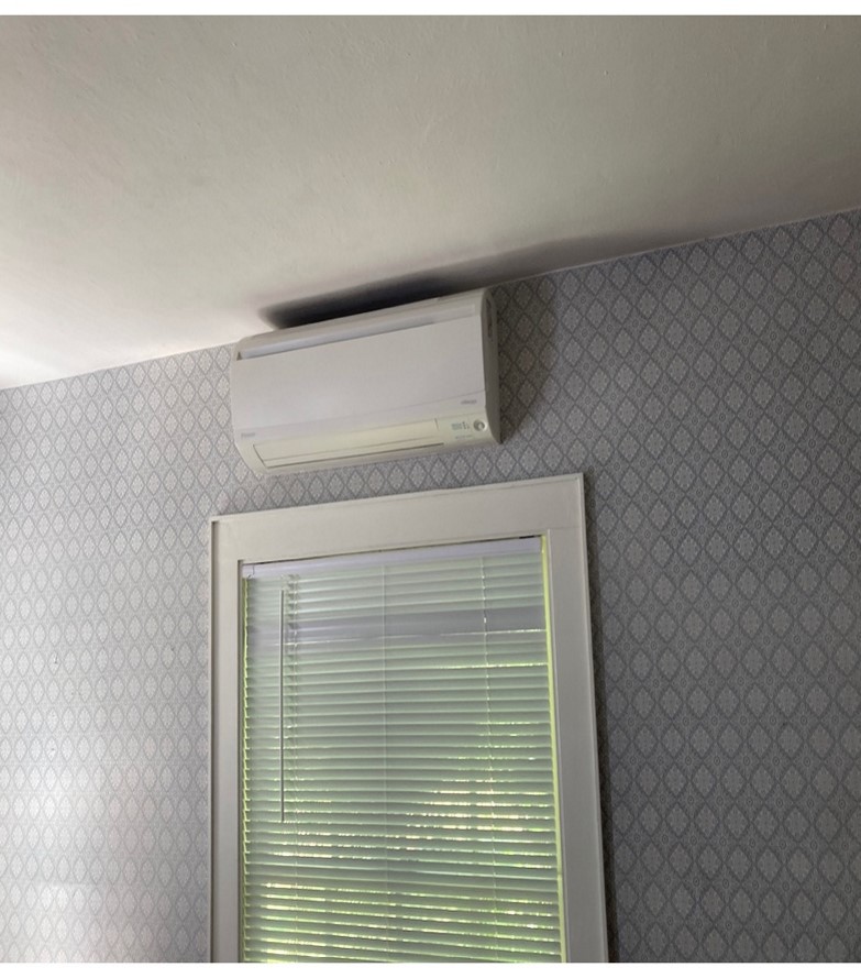 An overhead electric heat pump is on the wall over a window.