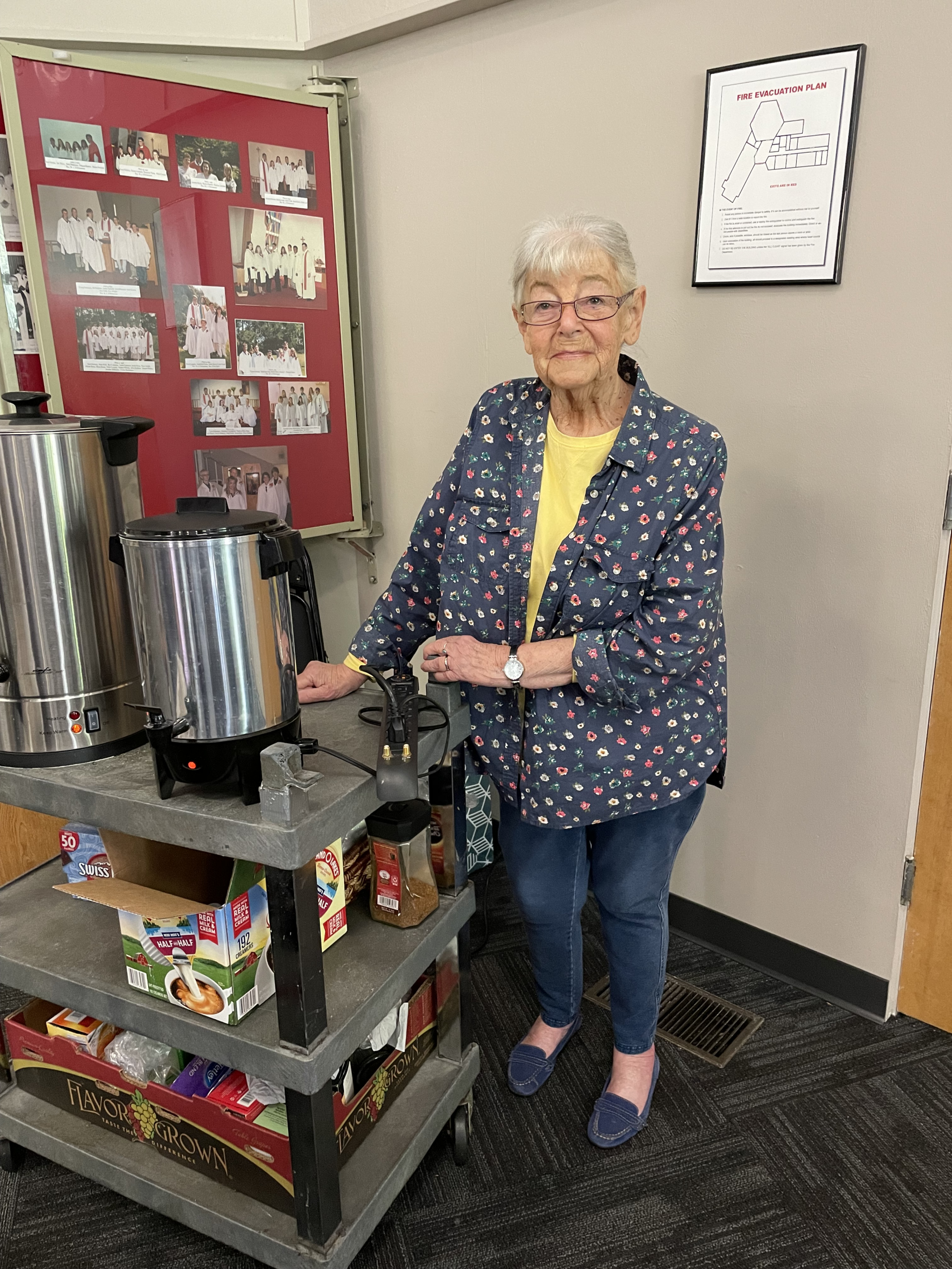 A woman stands beside a coffee station.