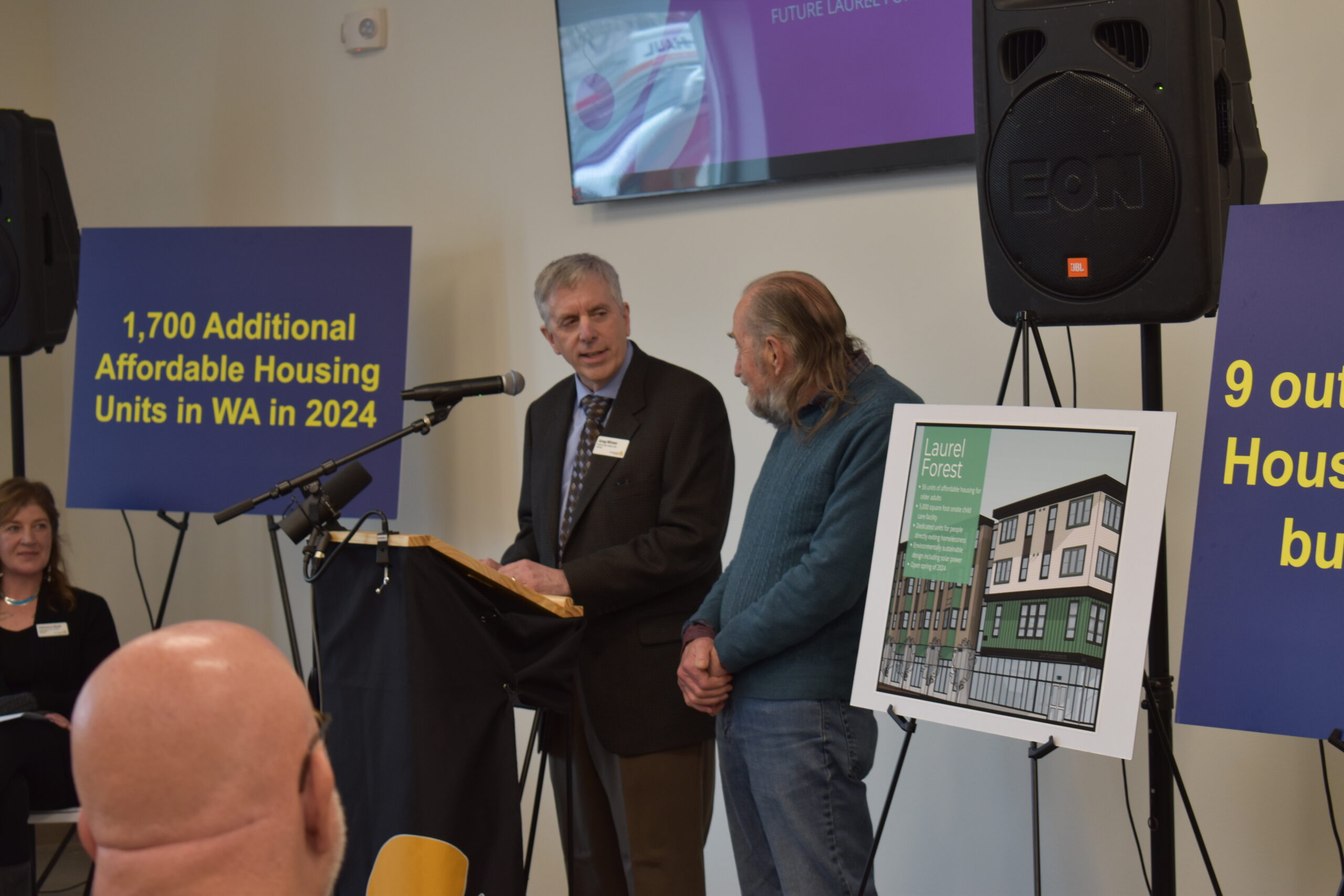 Two men stand side by side behind a podium and microphone.