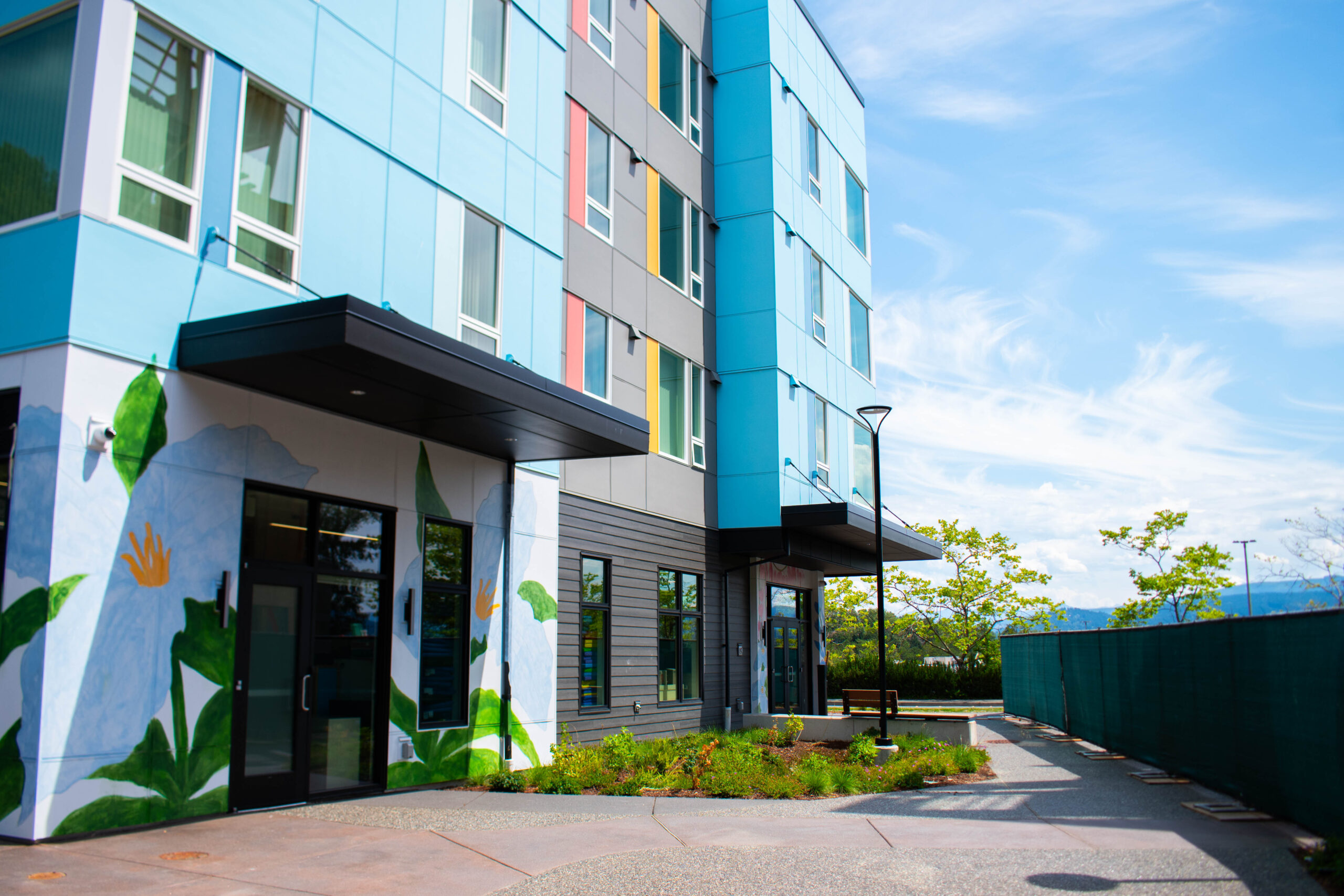 A blue apartment building with flower murals accentuating the walls