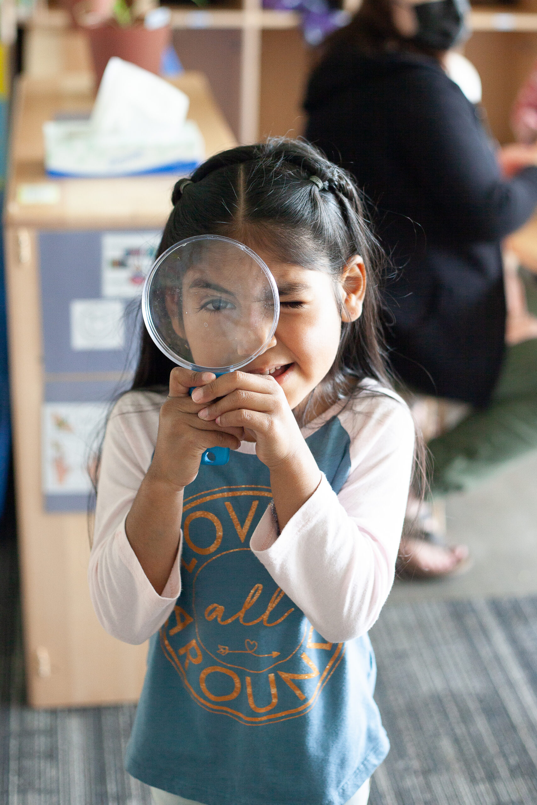 admin_page_MagnifyingGirl_2026-10-26 Little girl squinting curiously through a magnifying glass